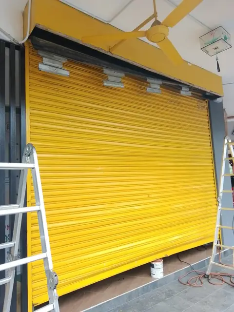 Yellow shop roller shutter after slat and guide rail repair